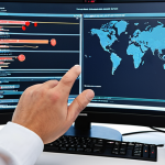 ** A security professional conducting a network security audit, examining firewall configurations and software updates on a computer screen. The setting is a modern office with network equipment visible in the background.

**
